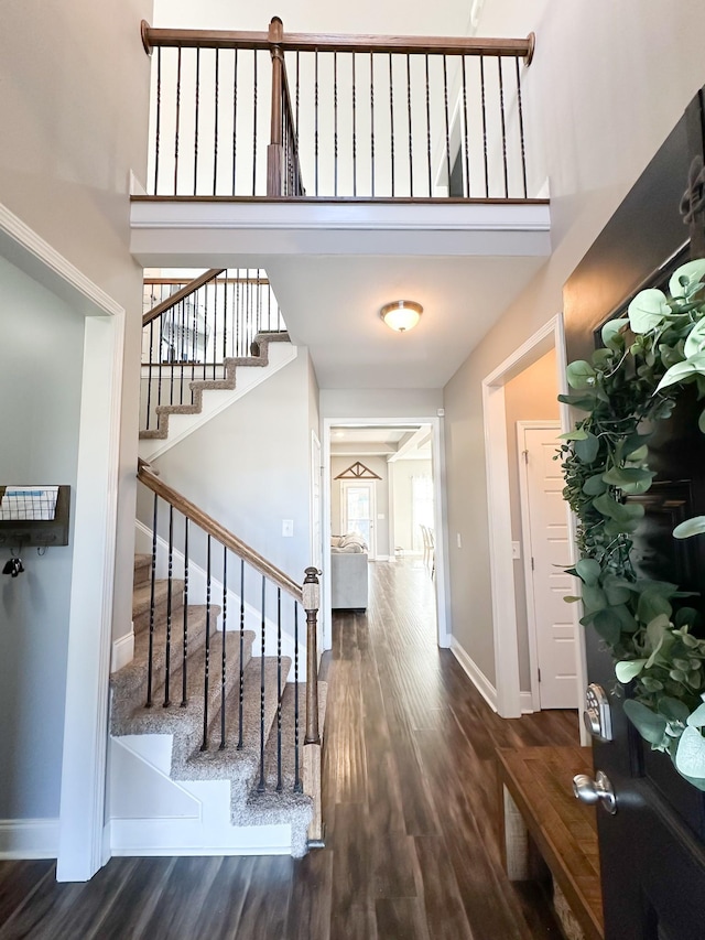 entryway with stairs, a high ceiling, baseboards, and wood finished floors