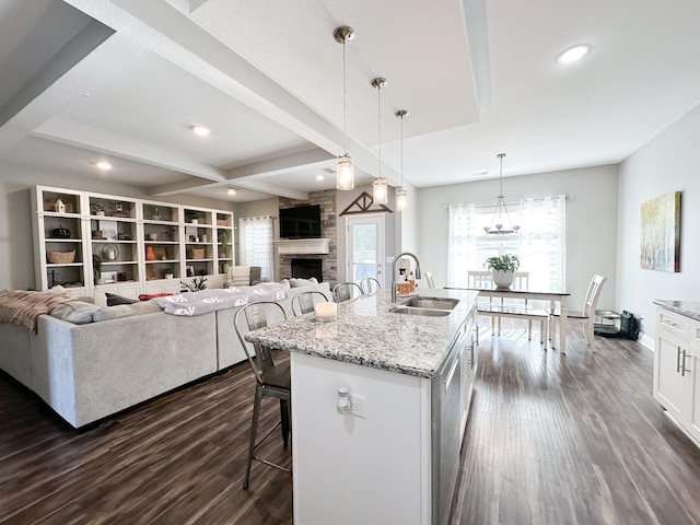 kitchen featuring a kitchen breakfast bar, dark wood-style flooring, a sink, a fireplace, and beam ceiling