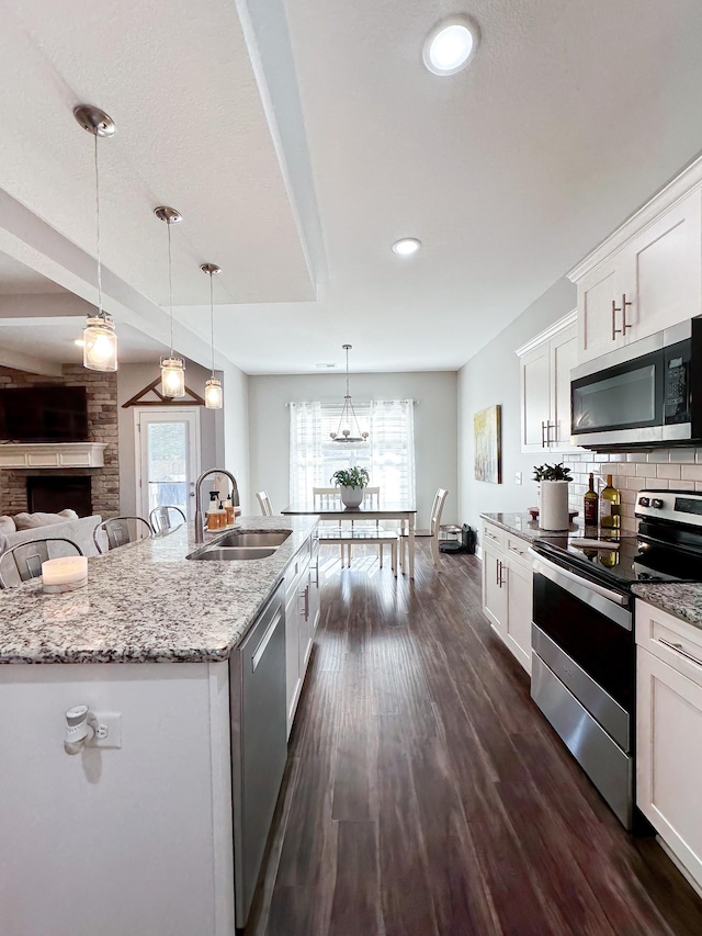 kitchen with dark wood-type flooring, a sink, white cabinetry, appliances with stainless steel finishes, and tasteful backsplash