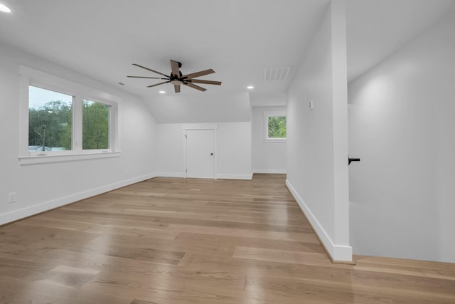 empty room featuring ceiling fan, visible vents, baseboards, vaulted ceiling, and light wood finished floors