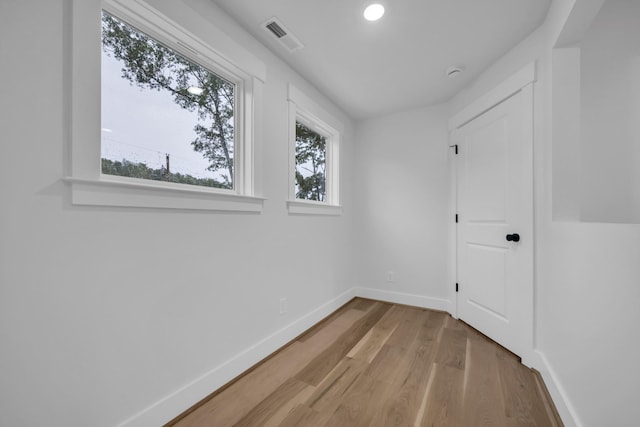 spare room featuring plenty of natural light, visible vents, baseboards, and wood finished floors