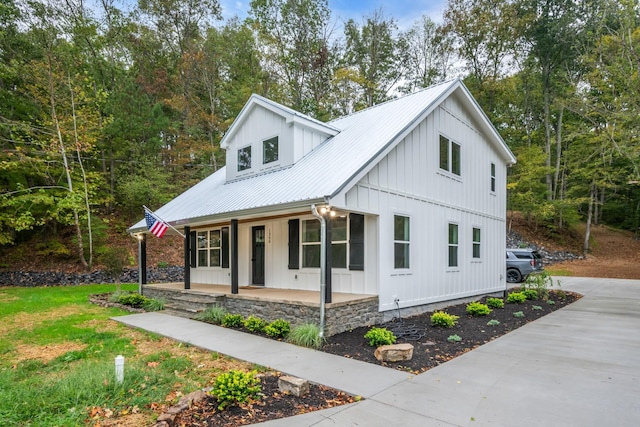 modern farmhouse style home with board and batten siding, covered porch, and metal roof