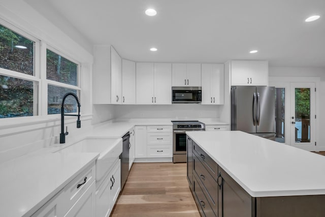 kitchen featuring white cabinetry, appliances with stainless steel finishes, light countertops, and a wealth of natural light