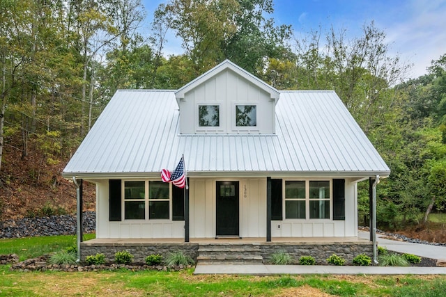 modern farmhouse featuring board and batten siding, covered porch, and metal roof