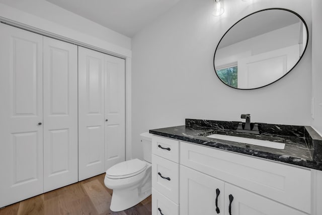 bathroom featuring a closet, vanity, toilet, and wood finished floors