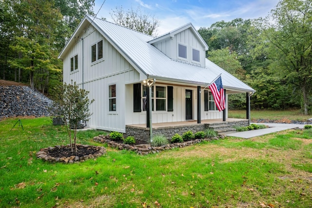 modern farmhouse style home with covered porch, metal roof, board and batten siding, and a front yard