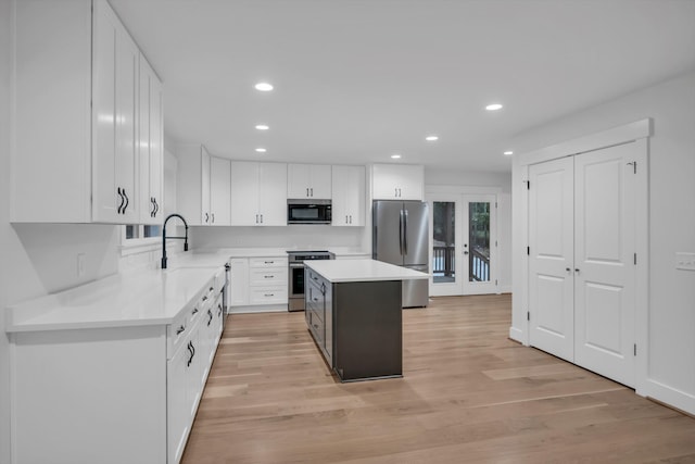 kitchen featuring french doors, appliances with stainless steel finishes, light wood-type flooring, and white cabinets