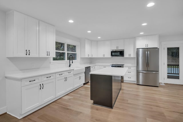 kitchen with appliances with stainless steel finishes, white cabinetry, and light wood-style floors