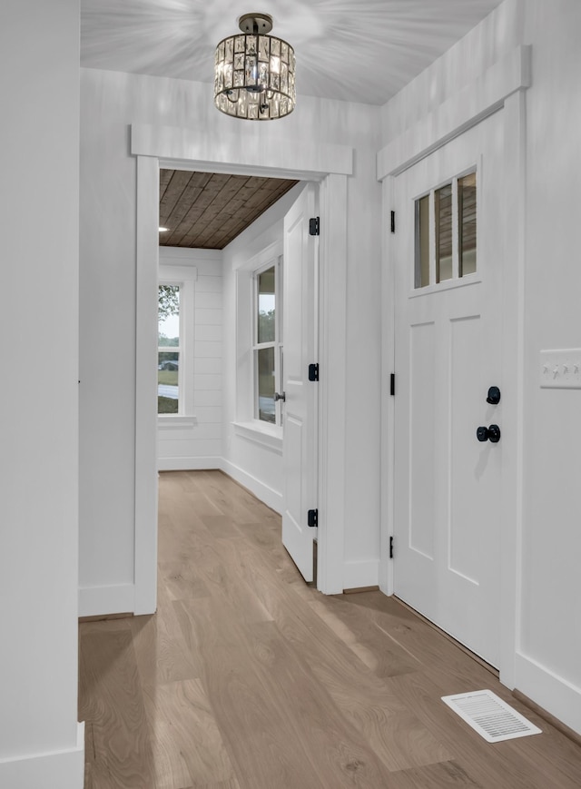 foyer featuring baseboards, visible vents, a chandelier, and wood finished floors