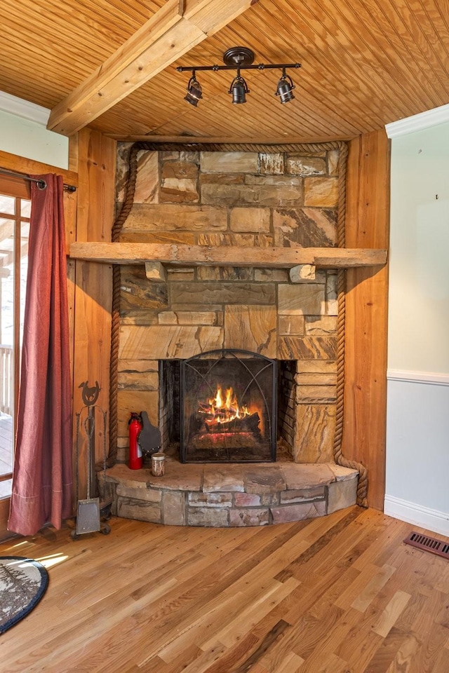 interior details with a fire extinguisher, visible vents, a stone fireplace, wood finished floors, and wooden ceiling