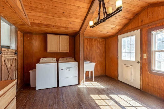 washroom with wooden walls, dark wood-style flooring, wood ceiling, washer and dryer, and cabinet space