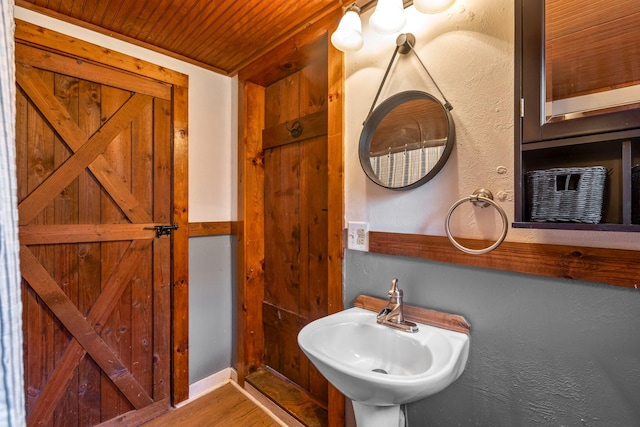 bathroom featuring wood ceiling, a sink, and wood finished floors