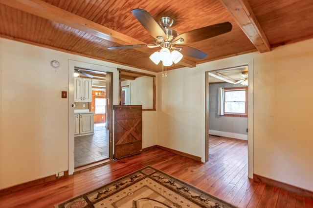 unfurnished room with wood ceiling, beam ceiling, hardwood / wood-style flooring, and baseboards