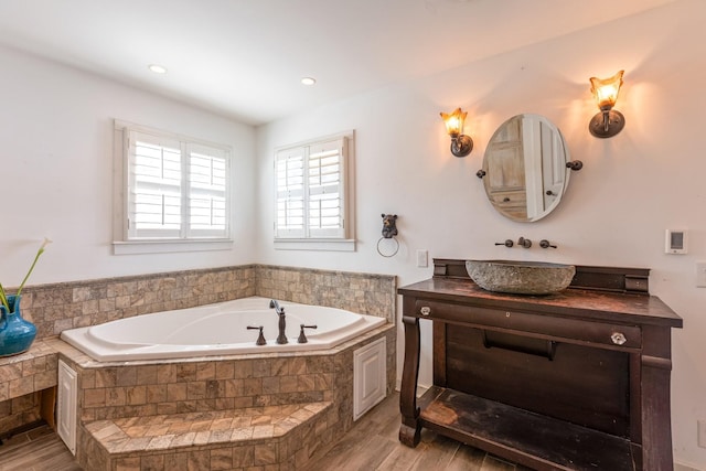 full bathroom featuring a garden tub, wood finished floors, and vanity