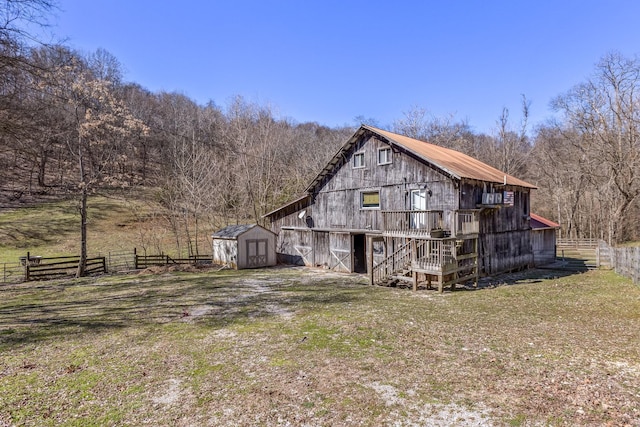 view of property exterior with a yard, an outdoor structure, a barn, and fence