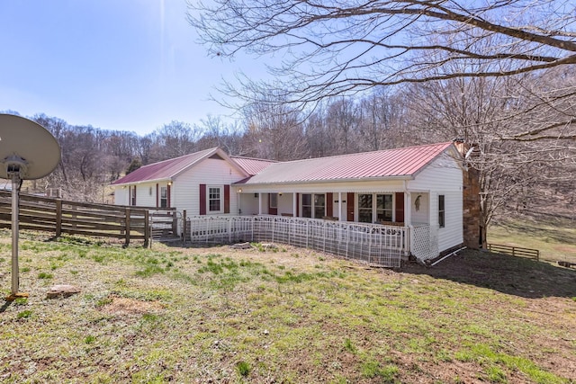 ranch-style house with covered porch, fence, and metal roof