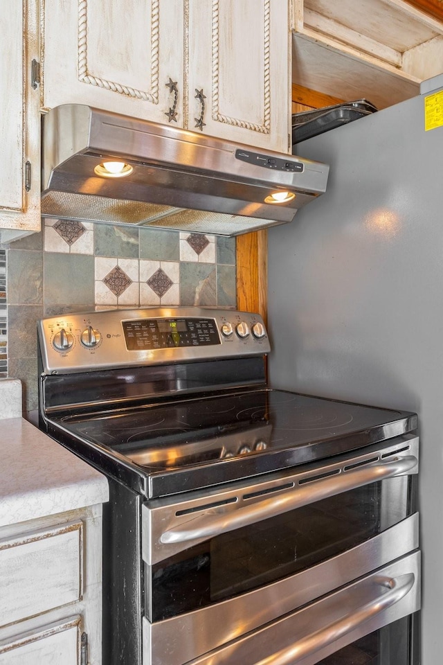 kitchen with range with two ovens, backsplash, and under cabinet range hood