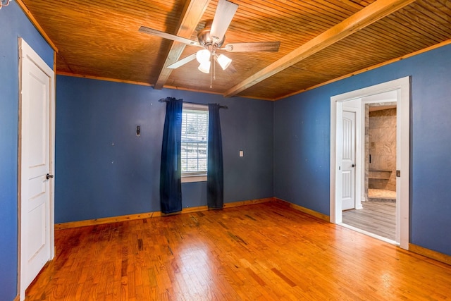 spare room with beamed ceiling, wood finished floors, a ceiling fan, and baseboards