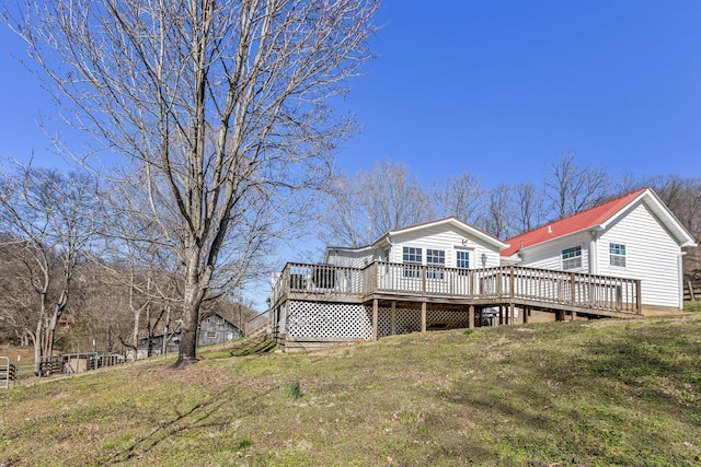 rear view of house with metal roof, a deck, and a yard