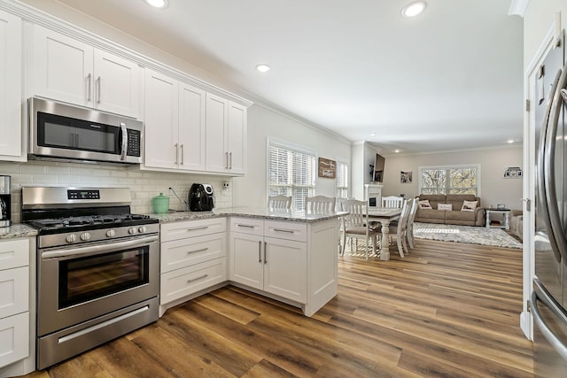 kitchen featuring a peninsula, appliances with stainless steel finishes, white cabinets, and backsplash