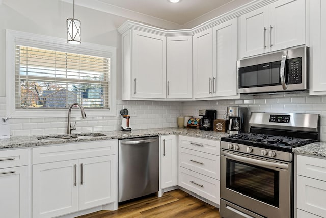 kitchen featuring backsplash, appliances with stainless steel finishes, white cabinets, a sink, and wood finished floors