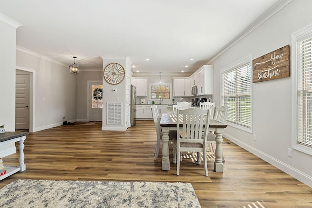 dining room with baseboards, wood finished floors, and crown molding