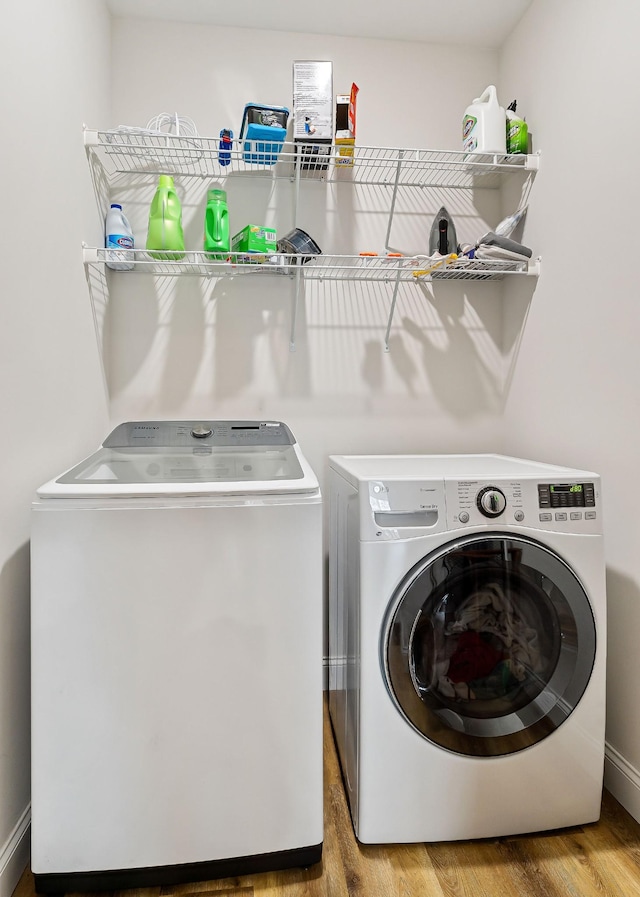 clothes washing area featuring washing machine and dryer, laundry area, and wood finished floors