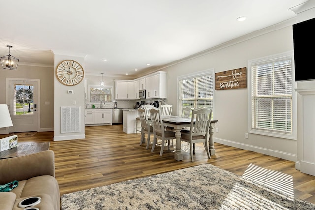 dining space featuring light wood finished floors, baseboards, visible vents, and ornamental molding