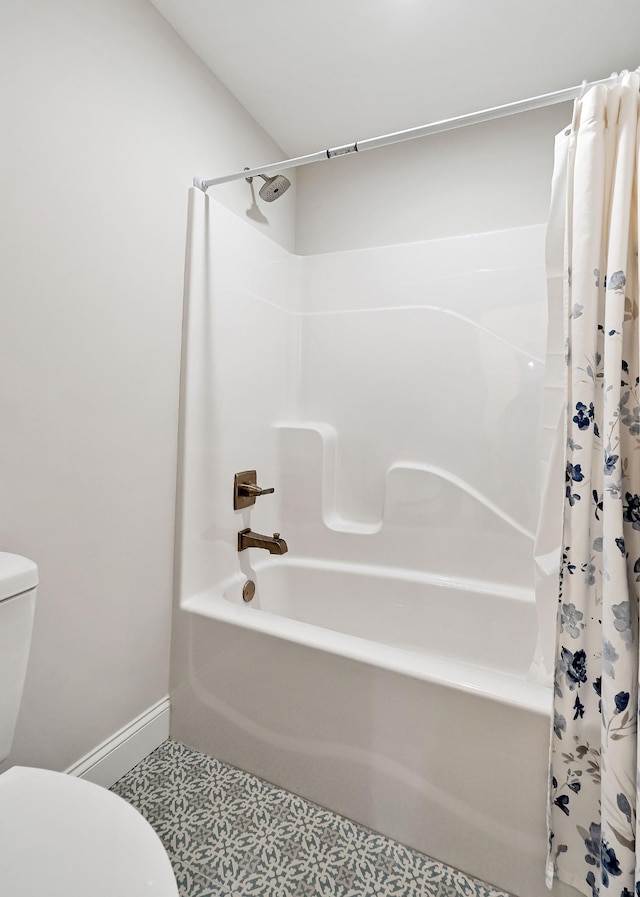 bathroom featuring shower / tub combo, toilet, and baseboards