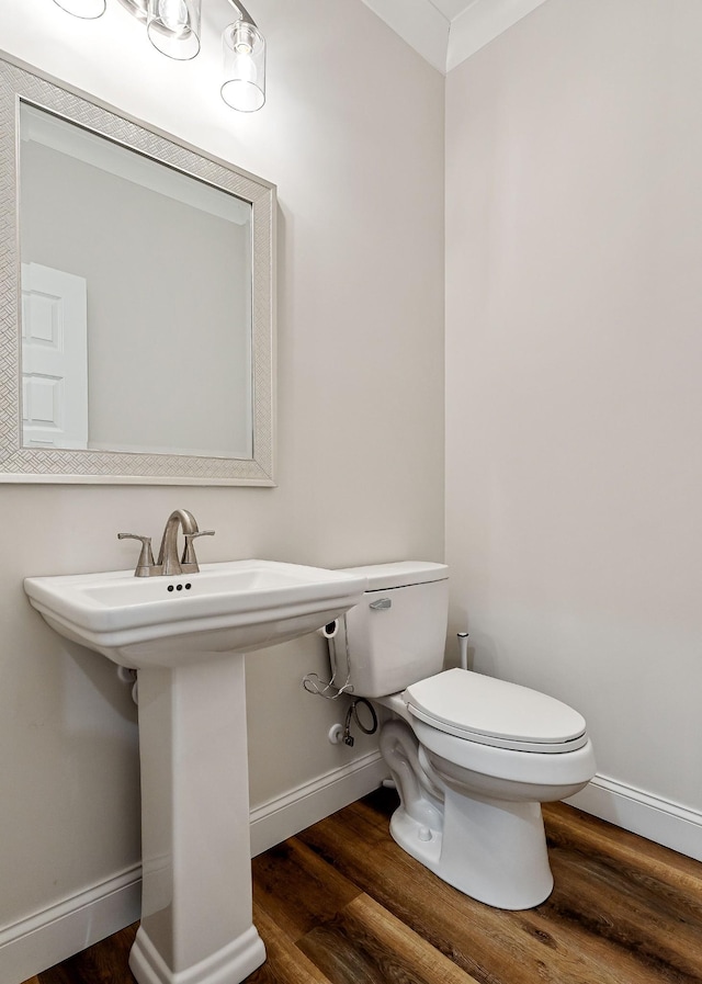 bathroom featuring a sink, wood finished floors, toilet, and baseboards