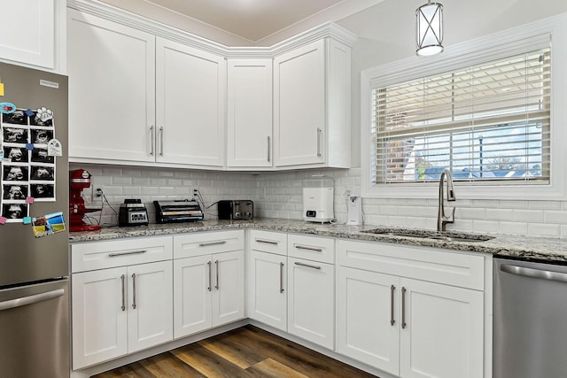 kitchen with stainless steel appliances, a sink, white cabinetry, and decorative backsplash