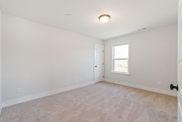 empty room with baseboards, visible vents, and light colored carpet