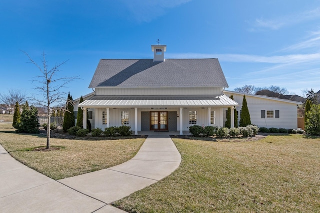 modern farmhouse with french doors, a porch, board and batten siding, a front yard, and metal roof