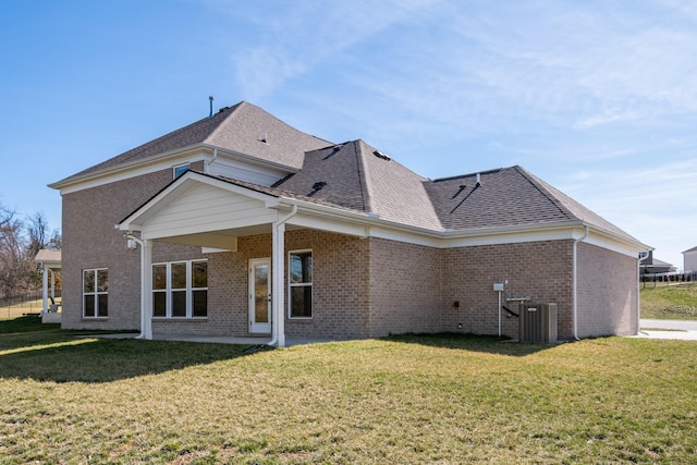 rear view of house featuring central AC, roof with shingles, brick siding, and a lawn