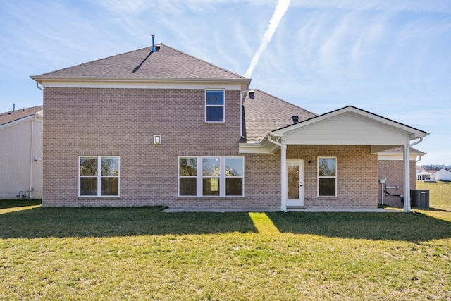 back of property with roof with shingles, brick siding, and a lawn