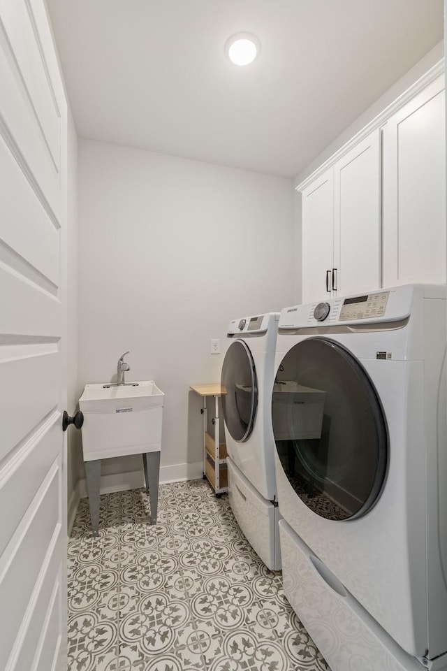 laundry room featuring washer and dryer, cabinet space, baseboards, and light tile patterned floors