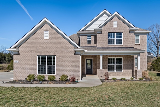 craftsman-style house with a porch, a front yard, and brick siding