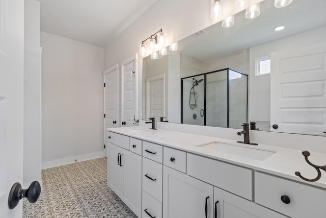 bathroom featuring double vanity, a stall shower, a sink, and tile patterned floors