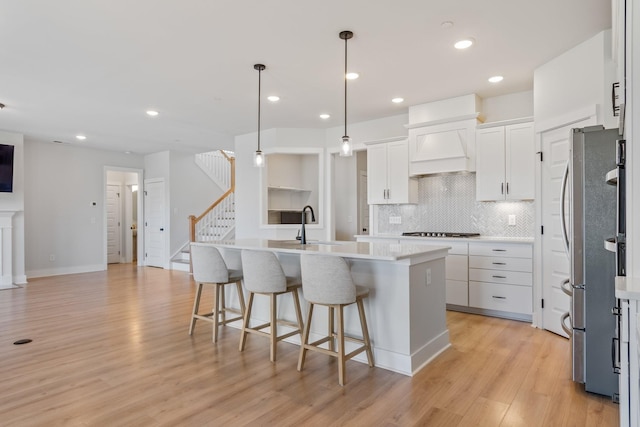 kitchen with custom exhaust hood, light countertops, a sink, and freestanding refrigerator