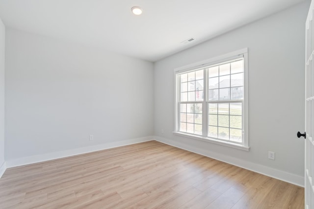 spare room featuring light wood-style floors, visible vents, and baseboards