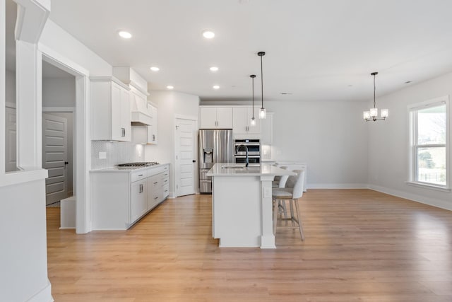 kitchen with stainless steel appliances, white cabinetry, a kitchen breakfast bar, light countertops, and light wood-type flooring