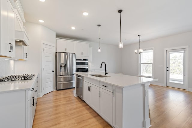 kitchen with light wood finished floors, white cabinetry, stainless steel appliances, and a sink