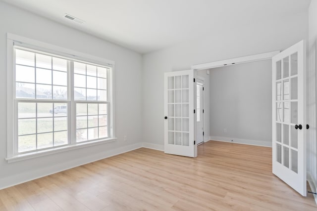 unfurnished room with light wood-style floors, french doors, visible vents, and baseboards