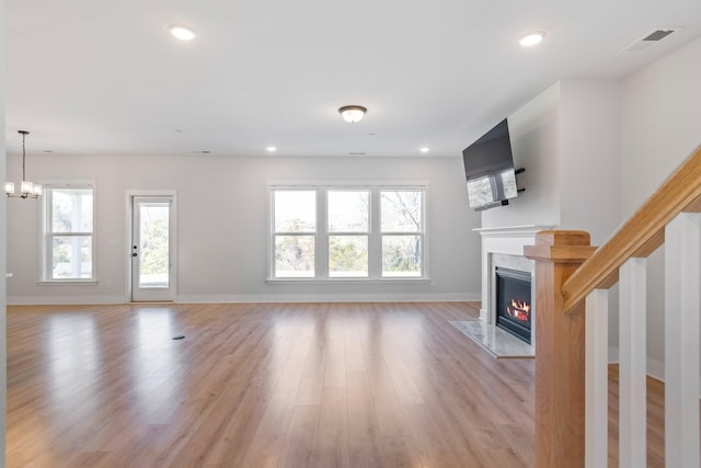 unfurnished living room with a healthy amount of sunlight, light wood finished floors, a premium fireplace, and recessed lighting