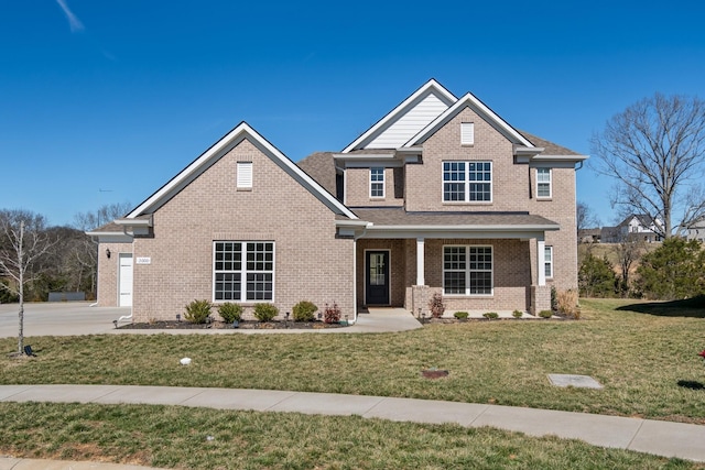 view of front of house with driveway, brick siding, roof with shingles, and a front yard