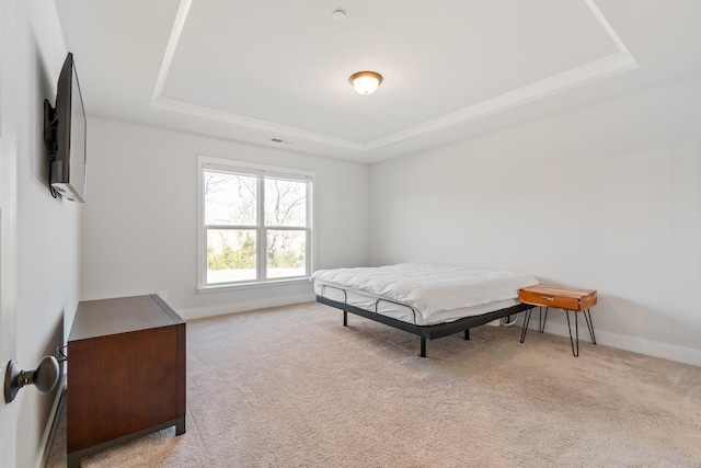 carpeted bedroom with baseboards and a raised ceiling