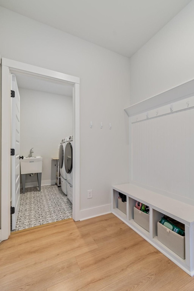 laundry room with washing machine and dryer, laundry area, a sink, wood finished floors, and baseboards