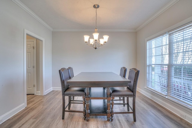 dining room featuring light wood-style flooring, crown molding, baseboards, and a notable chandelier