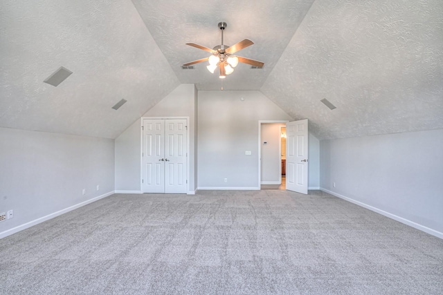 additional living space featuring lofted ceiling, a textured ceiling, visible vents, a ceiling fan, and baseboards