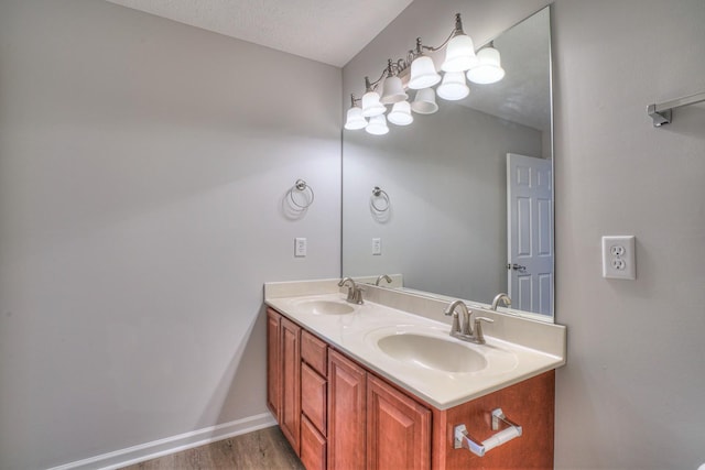 full bath with a sink, a textured ceiling, baseboards, and double vanity